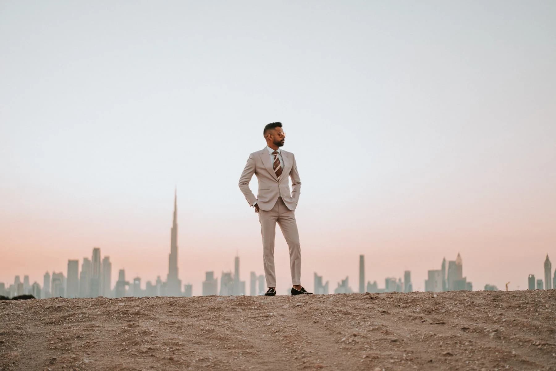 Landscape fashion photograph of a man in a light suit against the evening skyline